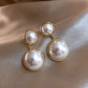 Close-up of pearl C-shaped gold hoop earrings on champagne silk background