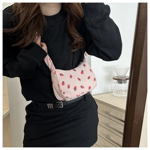 Detailed view of pink corduroy shoulder bag with strawberry print worn by a model