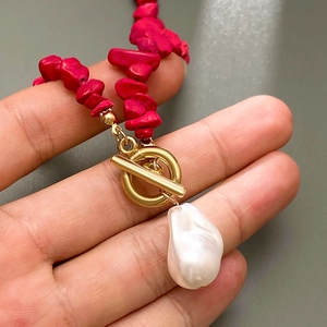 Detailed macro of red stone necklace with gold OT buckle and baroque pearl pendant