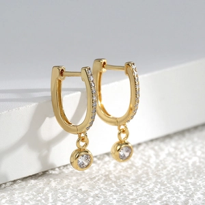 Elegant gold U-shaped earrings with micro-pave cubic zirconia on minimalist white background