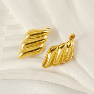 Chic 18K gold plated wing earrings on white plaster base with elegant soft lighting
