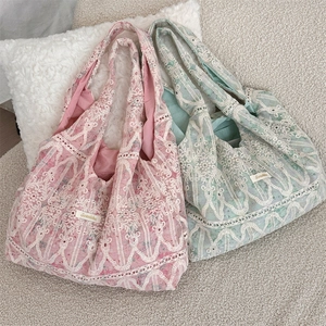 Close-up of vintage lace floral embroidery and brand label on pink and green tote bags