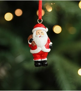Detail of Santa Claus resin ornament hanging on Christmas tree with warm bokeh lighting