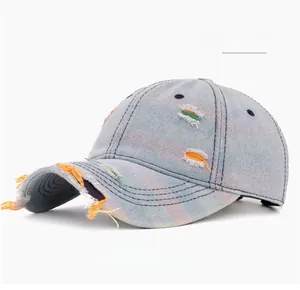 Close-up of light blue distressed denim baseball cap with frayed holes and contrast stitching