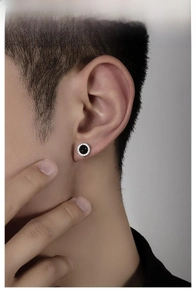 Close-up of a silver earring with a black stone center and white zircon halo detail