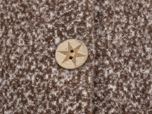 Close-up of vintage star-engraved wooden button on a textured knit cardigan coat