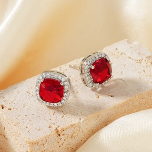 Men's cushion-cut red zircon stud earrings with micro-pave crystals on silk background