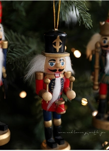 Detail eines 13cm Nussknacker-Soldaten aus Holz am Weihnachtsbaum mit goldenem Bokeh
