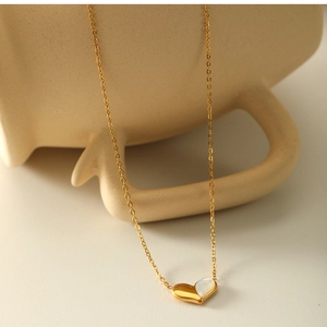 Detail shot of heart necklace with white shell inlay on a ceramic prop