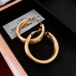 Close-up of gold plated hoop earrings with brushed matte texture in a black jewelry box