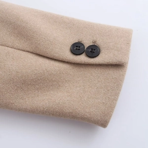 Detail der Wollmantel-Manschetten in Camel-Beige mit zwei schwarzen Zierknöpfen