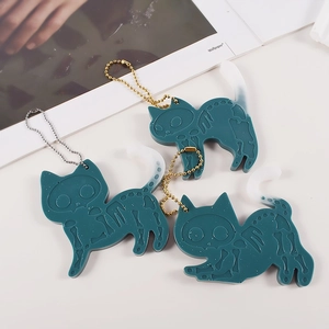 Three skeleton cat resin charms with metal chains on a minimalist magazine background