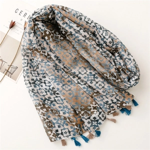 Lightweight gradient geometric scarf with tassels shown from a 45-degree flat lay angle