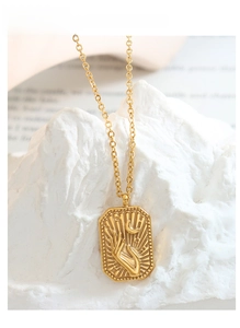 Detailed close-up of a gold rectangular pendant with moon hand relief on white stone