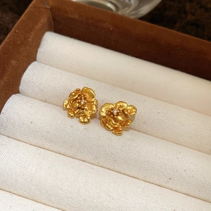 Macro view of 24K gold plated flower stud earrings featuring layered 3D petal details