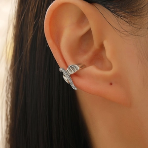 Detailed close-up of a vintage flying dragon ear cuff with intricate scale textures