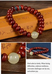 Détail du bracelet en santal rouge avec jade verte et perles bleues sur tapis bambou