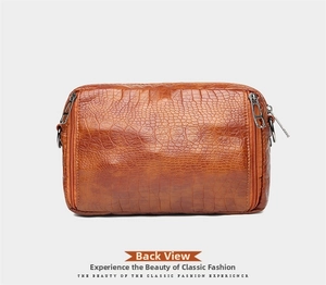Détail de la texture cuir de crocodile marron et du zip latéral du sac bandoulière rectangulaire