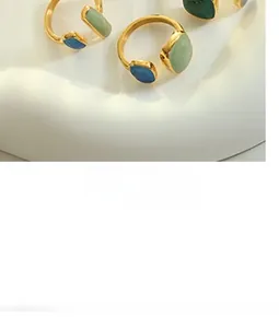 Close-up of adjustable gold open ring with green and blue enamel geometric charms
