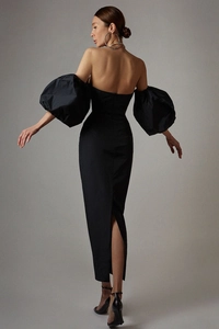 Back view of elegant off-shoulder black dress with lantern sleeves and a slit detail