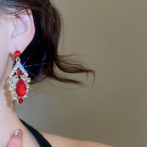 Close-up of elegant gold drop earrings with red and clear crystals on model's ear