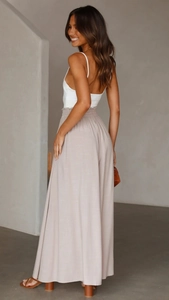 Détail du pantalon large beige à taille haute, avec un drapé souple et une ceinture élastique