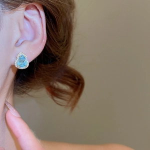 Vue détaillée de boucles d'oreilles gourde bleu clair avec de petits diamants