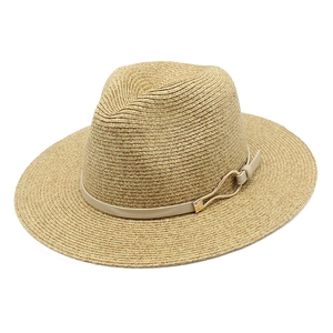 Detail of light woven Panama hat featuring beige faux leather band and gold metal buckle