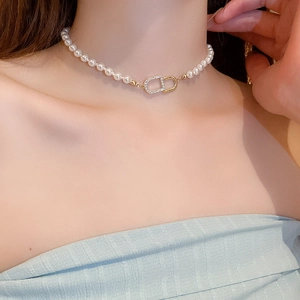Détail d'un choker en perles avec fermoir CD doré orné de zircons brillants et polis