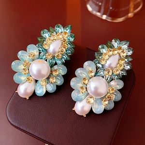 Détail de boucles d'oreilles fleurs vintage avec cristaux bleus et perles sur étui cuir