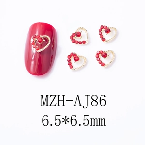 Vue macro de bijoux d'ongles coeur évidé 6,5mm avec strass rouges et base dorée