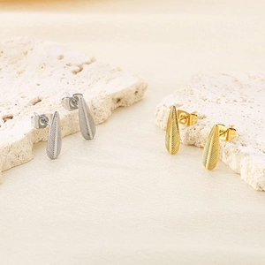 Détail macro de boucles d'oreilles feuilles en acier inoxydable dorées et argentées