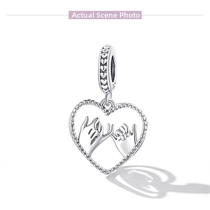 Macro detail of S925 sterling silver charm with pinky swear hand-in-hand heart design