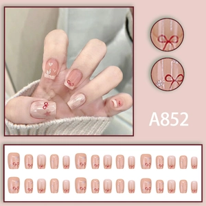 Detail view of pink press-on nails with red bow designs and silver heart glitter accents