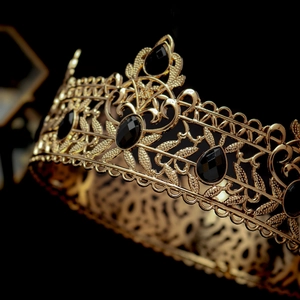 Detail of baroque gold crown with hollow leaf patterns and black oval gemstones
