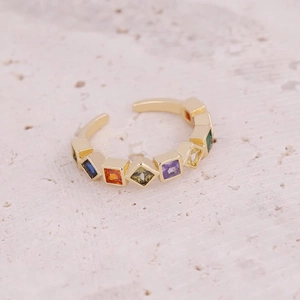 Detail of adjustable gold ring with rainbow cubic zirconia on a natural stone surface