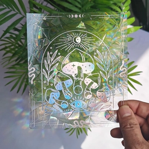 Detailed holographic suncatcher sticker featuring mushrooms and moon patterns held by hand