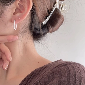 Close-up of twisted rope texture U-shaped silver earring on a model with knitwear