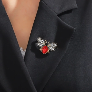 Close-up of cute bee brooch with red gemstone on black blazer lapel for winter styling