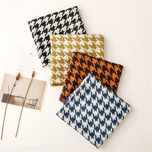 Detail showing four colors of houndstooth scarves with refined stitching on a white desk