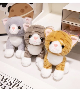 Close-up of three soft plush kittens in grey, brown, and orange stripes with realistic eyes