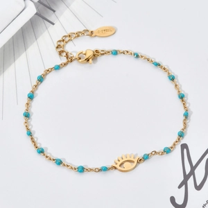 Detailed macro view of gold-plated stainless steel evil eye pendant with blue beads