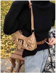 Detail of khaki motorcycle shoulder bag with vintage metal buckles and glossy leather texture