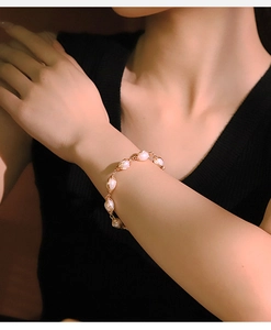Detailed view of an elegant gold metal chain bracelet with white freshwater pearls for women