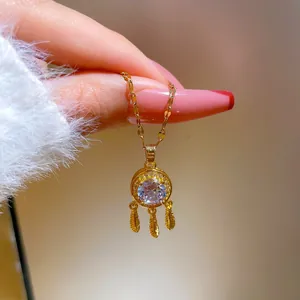 Close-up of golden dreamcatcher necklace featuring a zircon center and feather tassels