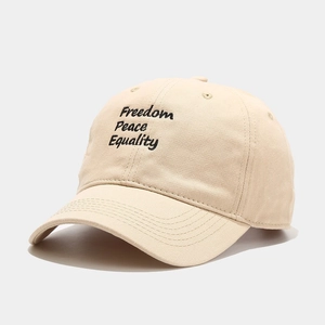 Close-up of the Freedom Peace Equality embroidery on the beige cotton baseball cap