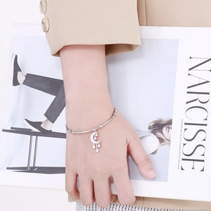 Detail of silver steel bracelet with moon and star pendants on a fashion magazine