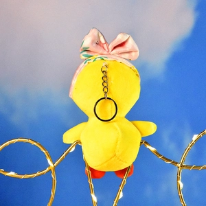 Back view of a cute yellow plush duck keychain with a pink floral bow headband