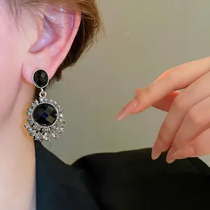 Vintage black gemstone earrings with silver diamond frame on a female model