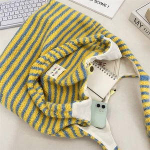 Detailansicht der gelb-blau gestreiften Plüschtasche mit Stoffetikett und Druckknopf